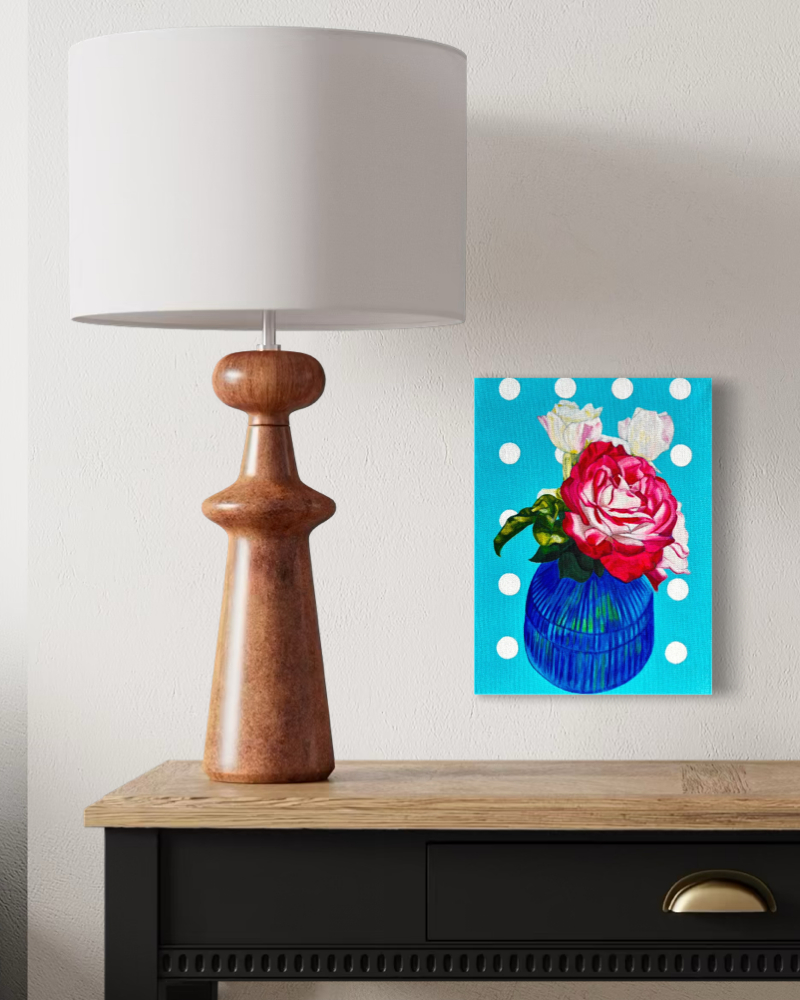 Decorative lamp with a colourful original floral painting on a wall above a wooden table.