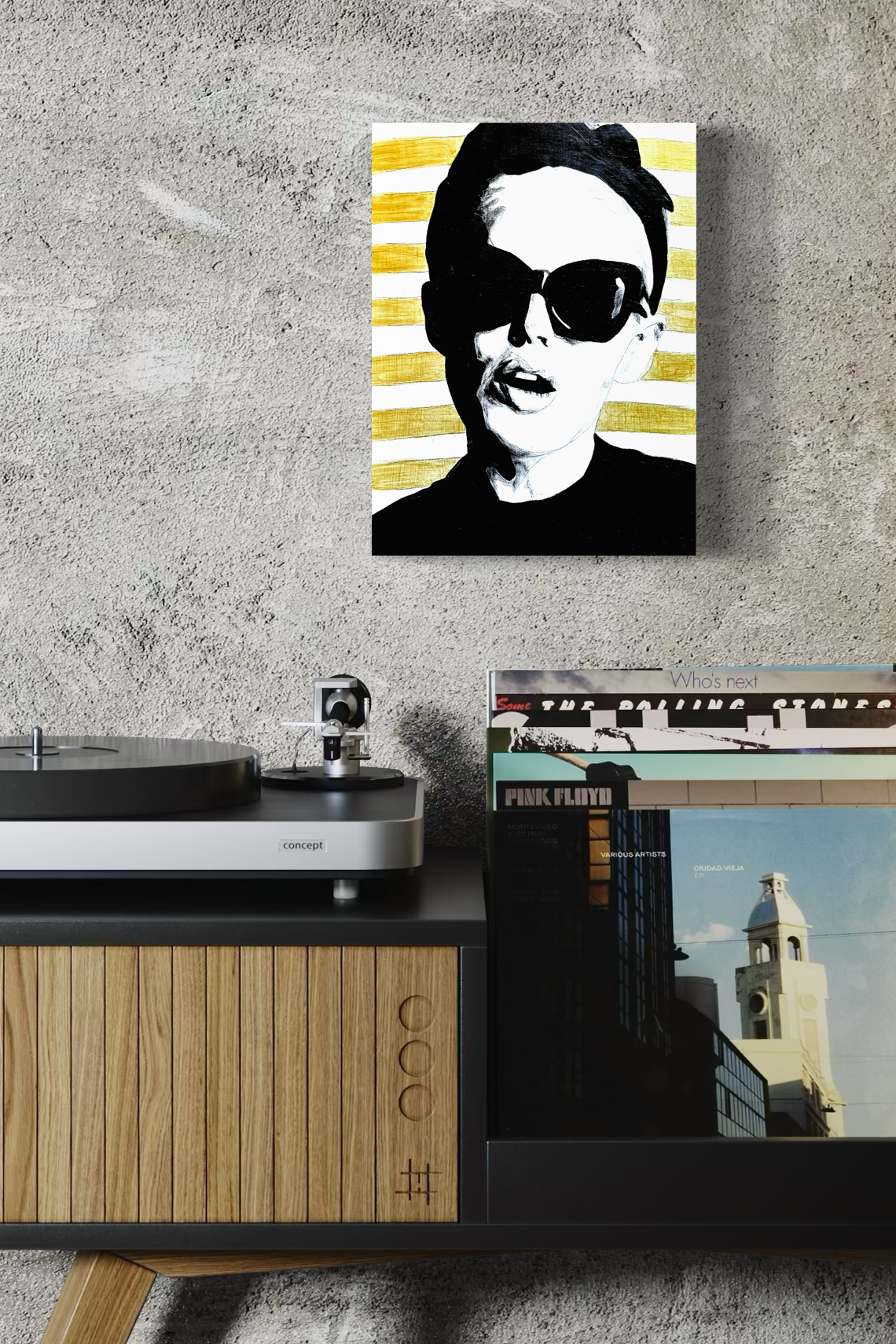 Original painting on board of a woman wearing sunglasses on a wall above a record player and records.