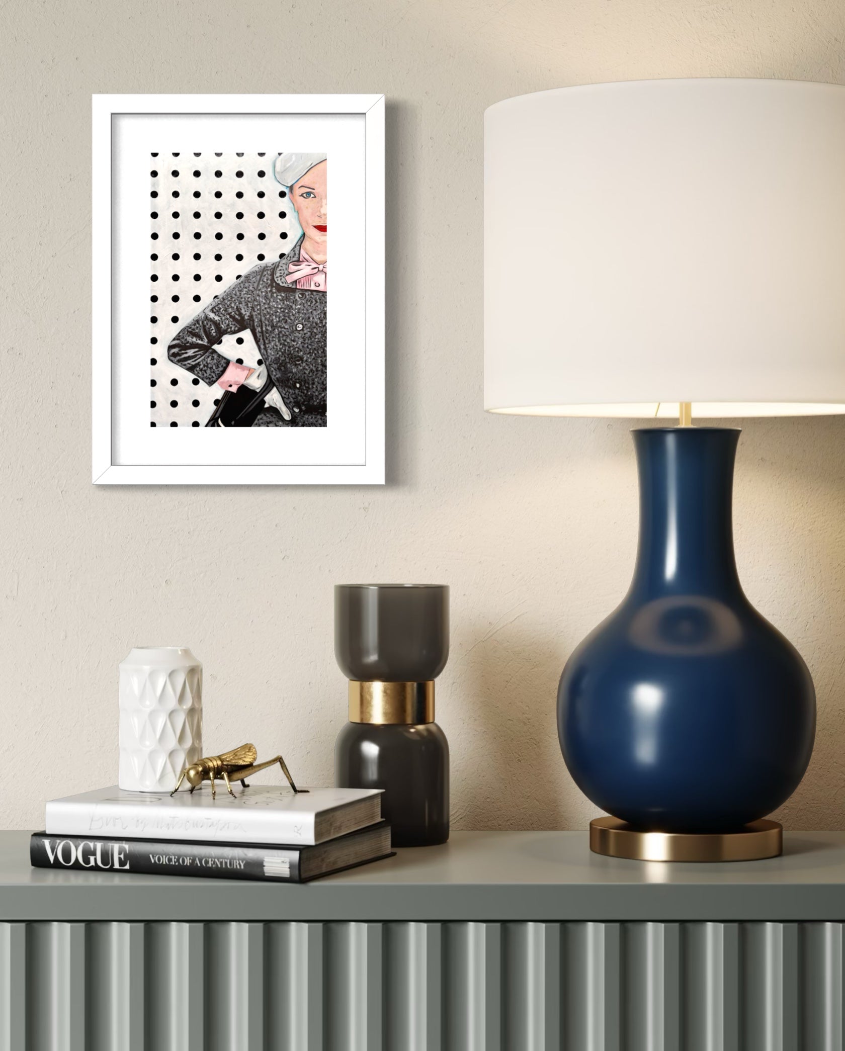 Navy blue lamp on a shelf with decor items and a framed limited edition print on the wall. 