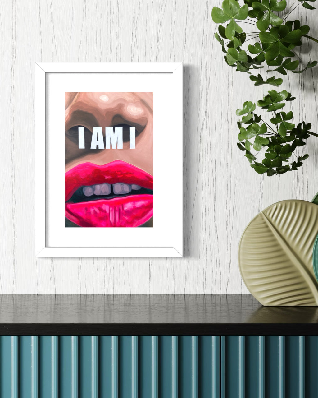 Framed artwork of a limited edition print with a close-up of lips and the text 'I AM I' on a wall with decorative elements.