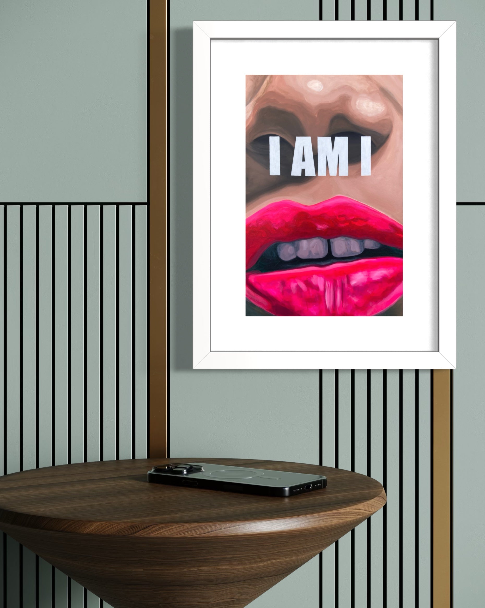 Framed limited edition print with a close-up of lips and 'I AM I' text on a wall above a wooden table.