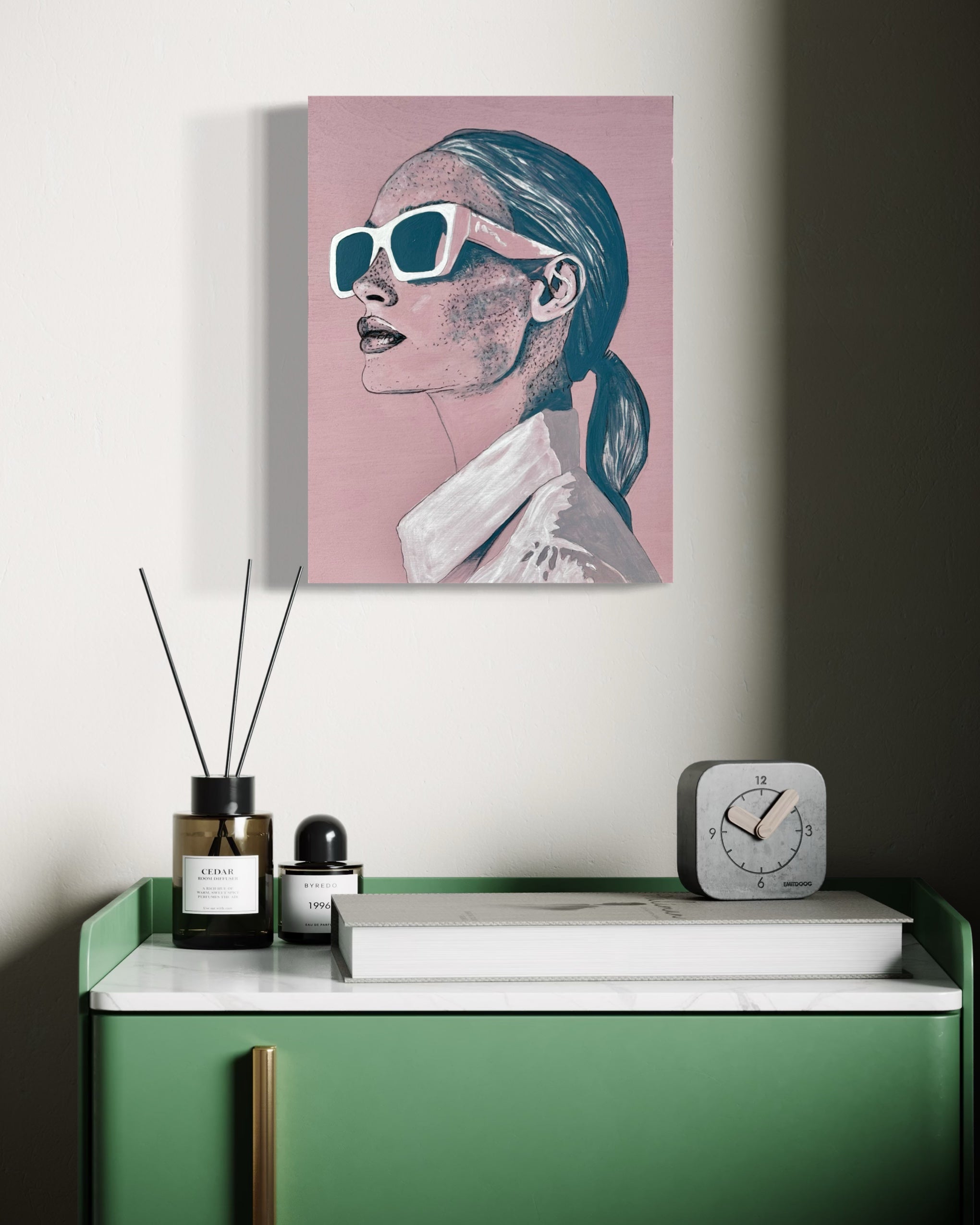 Modern interior with a green console table, decorative items, and a canvas painting on the wall of a woman wearing sunglasses, Frankie'.