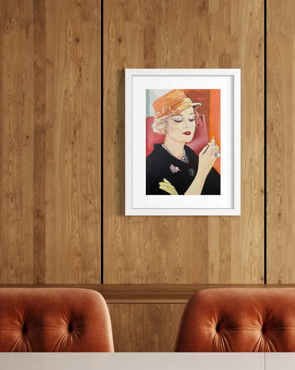A framed art print featuring a stylized portrait of a woman in a black outfit and orange hat, displayed on a wood-paneled wall above two tufted orange-brown chairs.