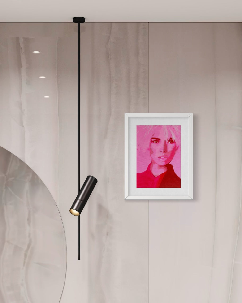 A framed art print featuring a stylized portrait in vibrant pink and red tones, hung on a light beige marble wall next to a modern black pendant light.