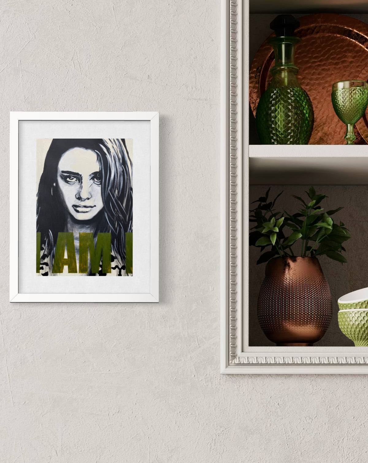 A framed art print featuring a black and white portrait of a woman with olive green text overlay, displayed on a textured light gray wall next to a shelf with decorative green and copper-colored vases.
