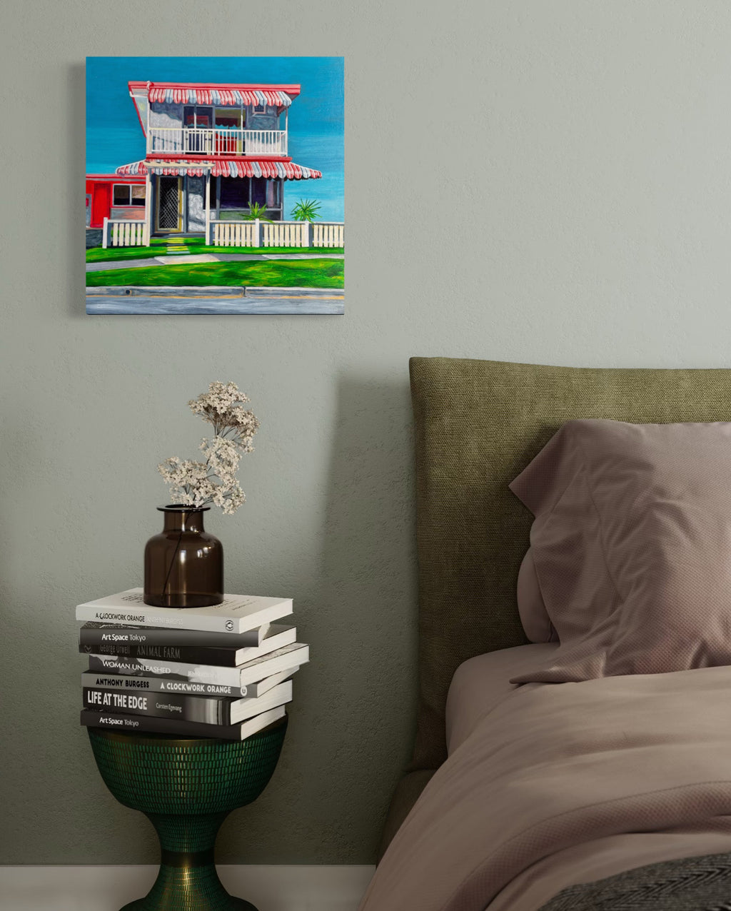 'The Classic' by Annie Pritchard displayed beside a bed with an olive headboard and a stack of books.