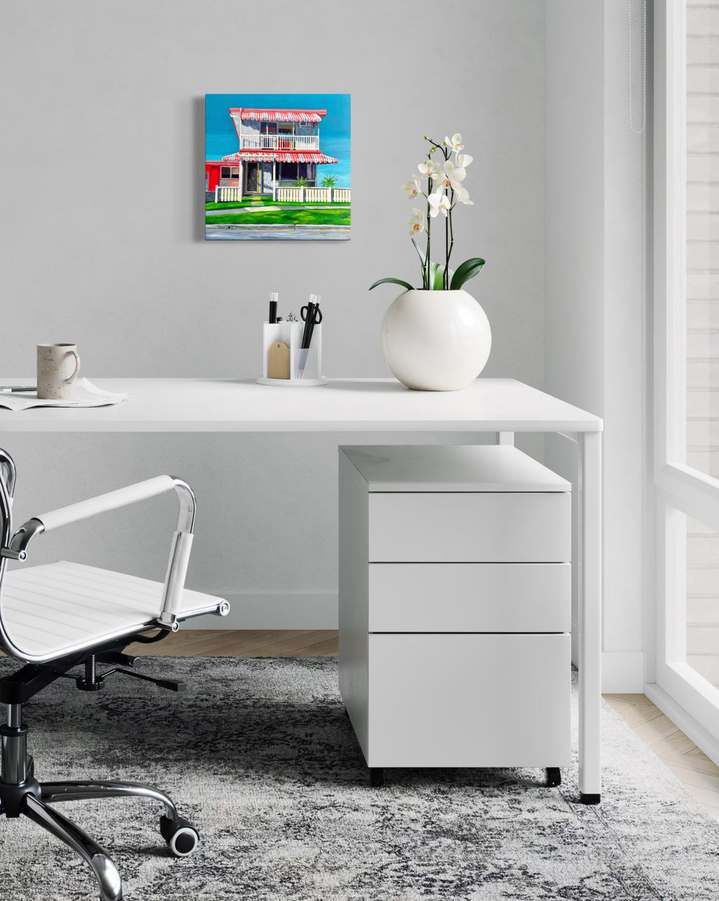 'The Classic' by Annie Pritchard displayed above a white desk beside a white orchid.